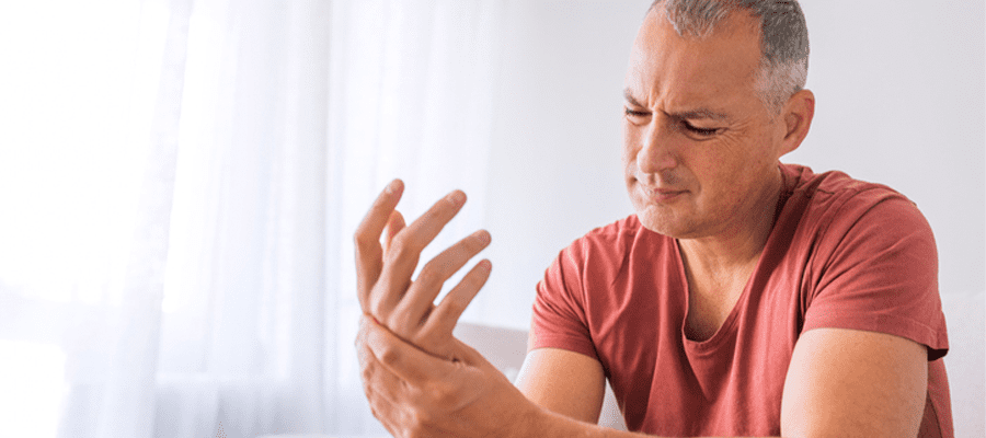 Un homme souffre de douleurs aux mains causées par des rhumatismes