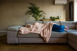 Une femme est couchée sous une couverture dans le canapé
