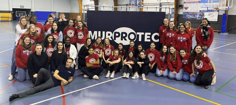 U14/U16/U19 meisjesploegen bij Royal Nivelles Basketball staan voor een vlag van Murprotec