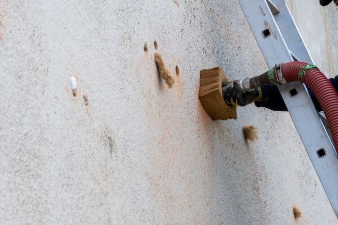 Lance dans le mur pulvérisant de l'isolant dans la cavité