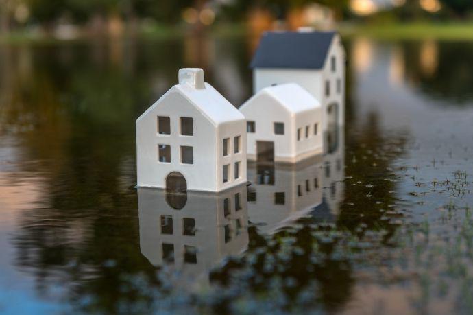 Drie witte speelgoedhuisjes naast elkaar op een straat die nat is door de regen