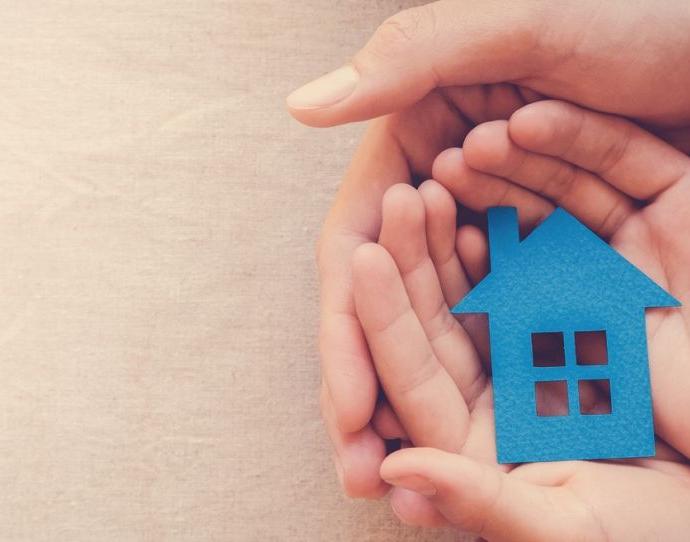Les mains d’un adulte et d’un enfant tiennent une maison en papier bleu