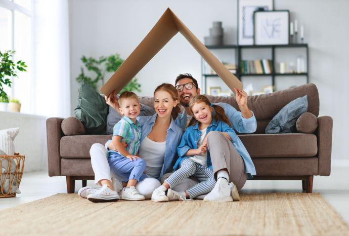Un père tient un toit en carton au-dessus des têtes de sa famille heureuse