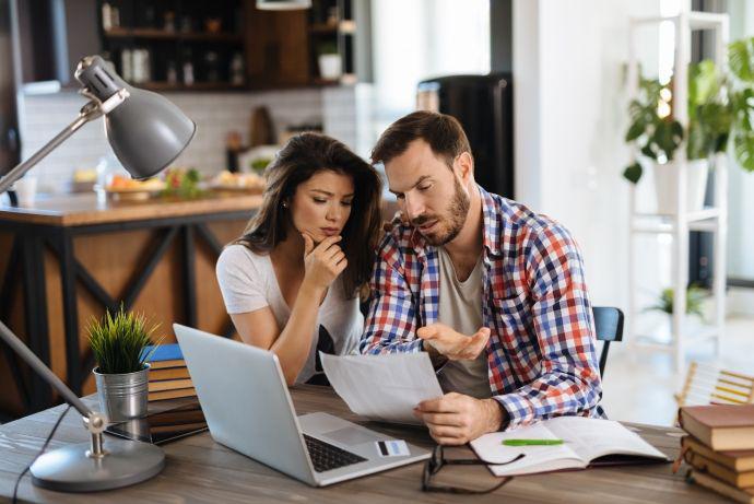 Un jeune couple frustré contrôle ses factures à domicile avec l’ordinateur portable