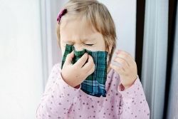 Une petite fille se mouche dans un mouchoir vert